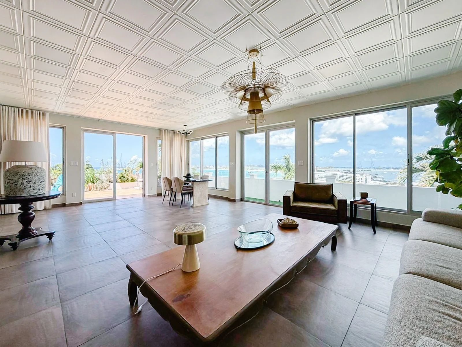 Main living room with wraparound floor-to-ceiling windows overlooking Pelican Bay