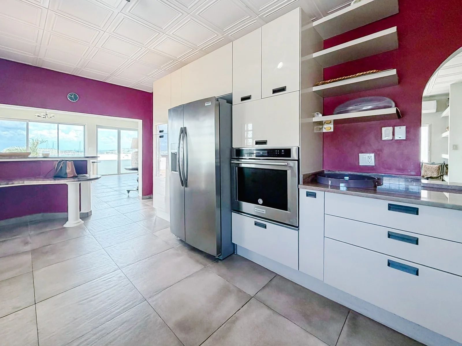 Kitchen with burgundy walls, side-by-side stainless fridge and double wall oven, view to dining area beyond