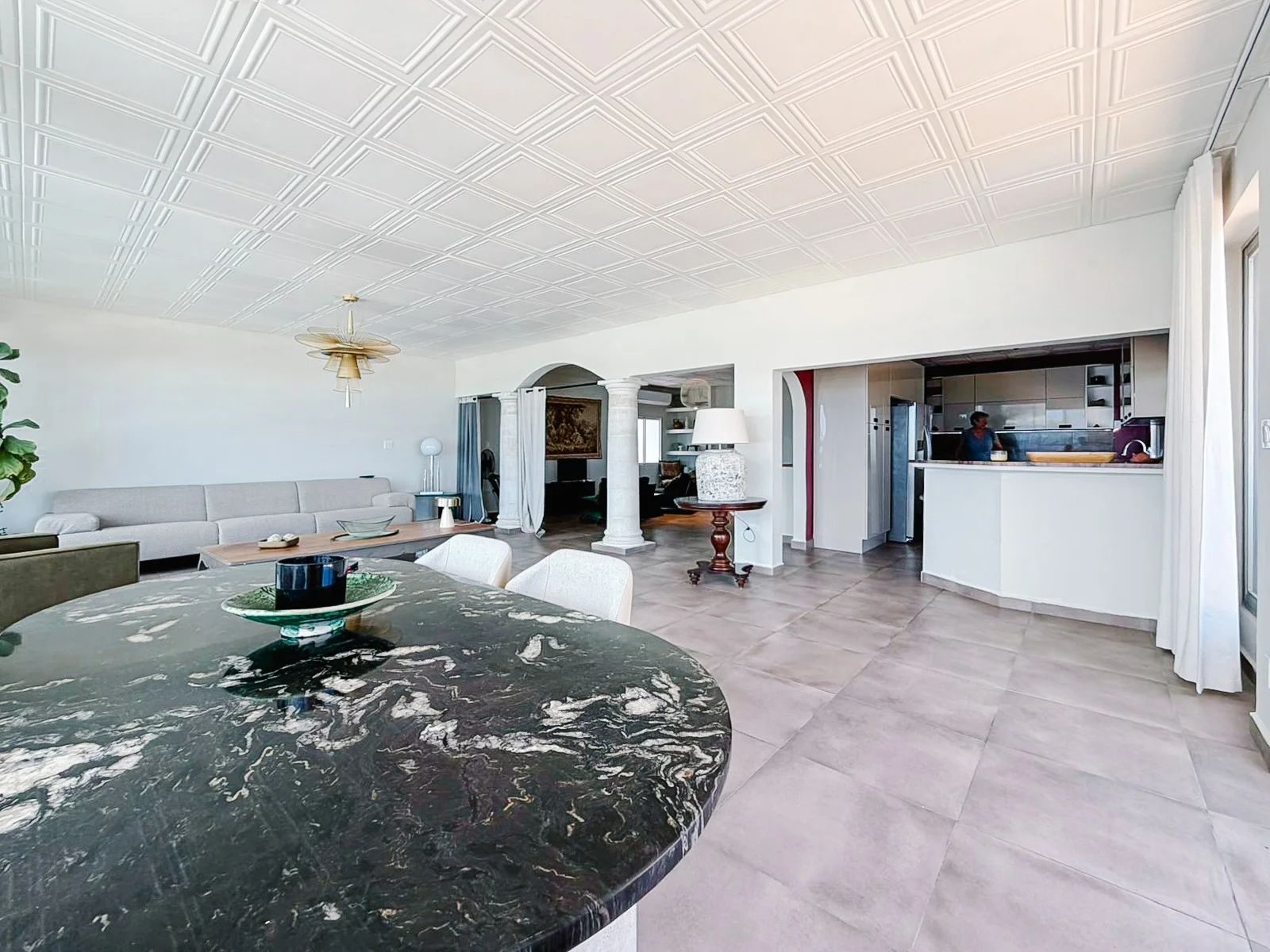 Open plan from dining toward den and kitchen, columns and coffered ceiling