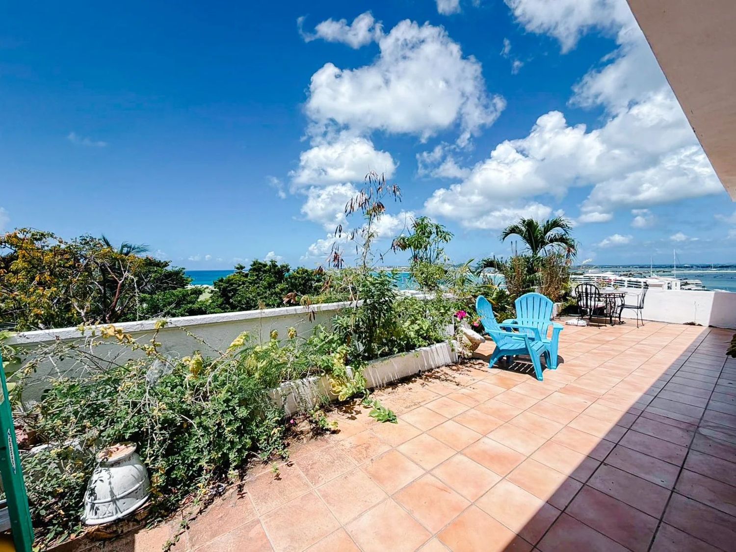 Wide terrace with turquoise Adirondack chairs and tropical garden