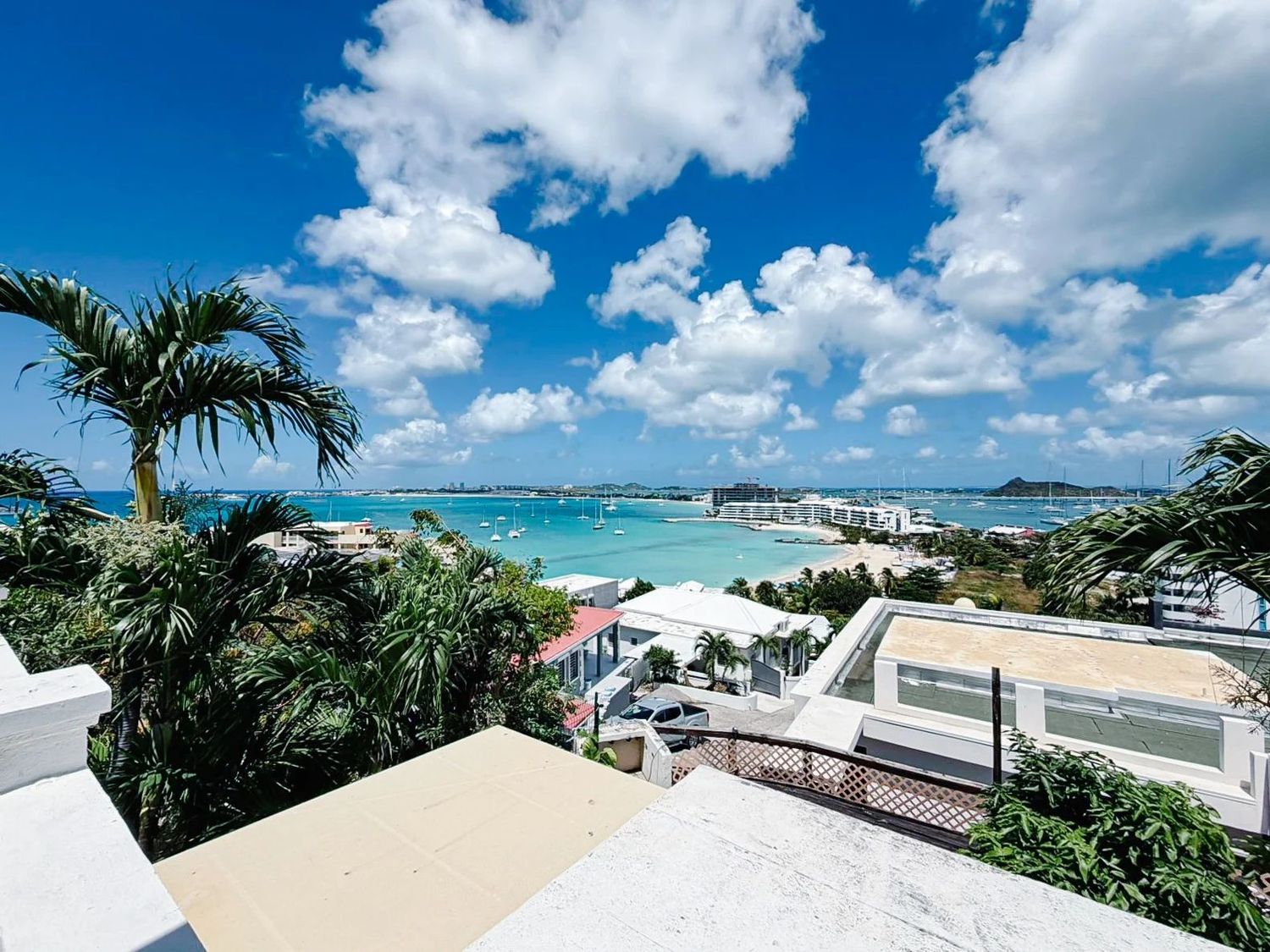 Panoramic view of Pelican Bay with sailboats, beach, and distant mountains