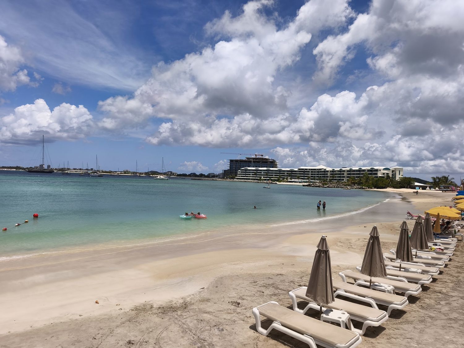 Wide panorama of Pelican Bay beach with yellow umbrellas