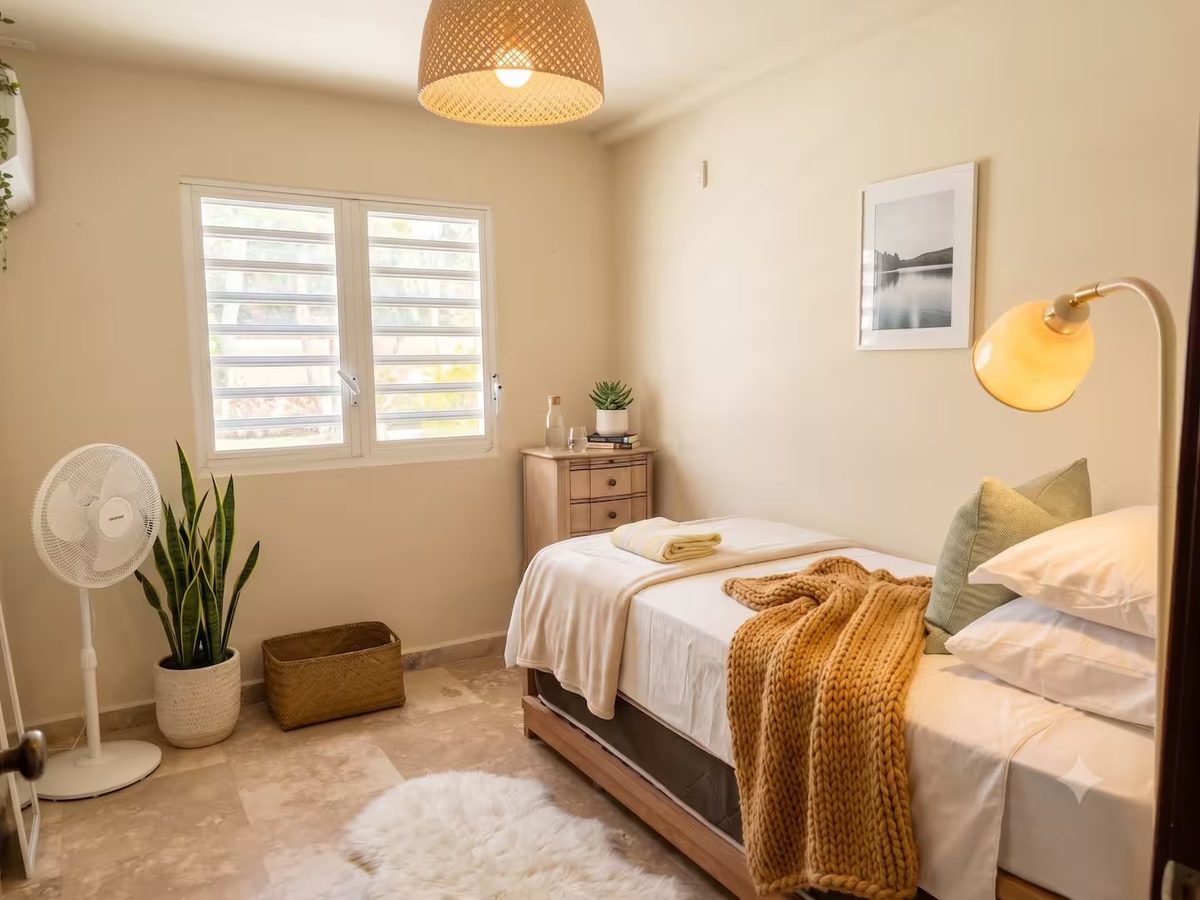 Full bedroom with a wooden bed, knitted mustard throw, chest of drawers and shuttered window